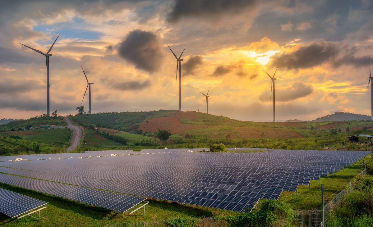 Clean Energy - Solar Panels and Wind Turbines in a field at sunset